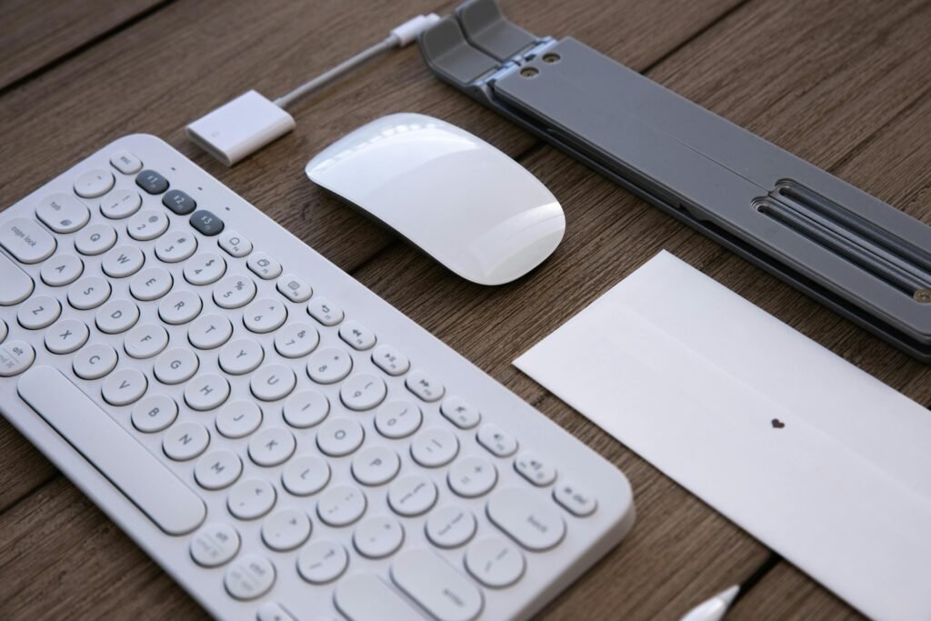 A sleek workspace setup featuring a wireless keyboard, mouse, and adapter on a wooden desk.